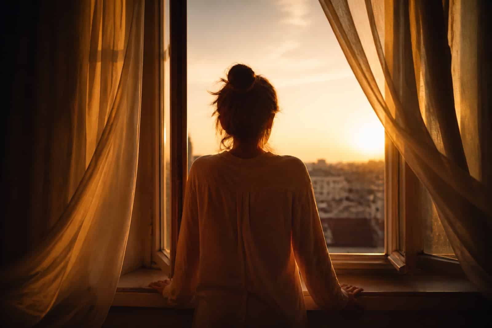 Person at an open window at sunrise